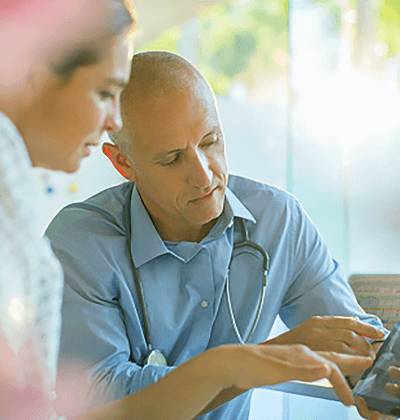 Male physician showing female patient data on his smart device